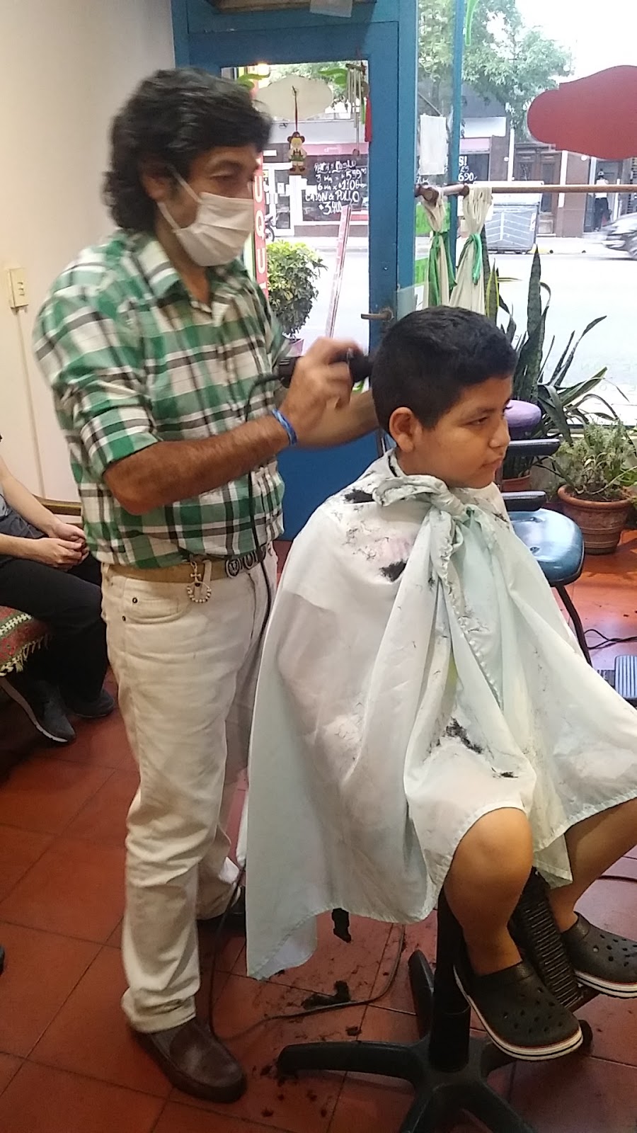Mateo cortándole el pelo a un nene en Peluquería Mateo