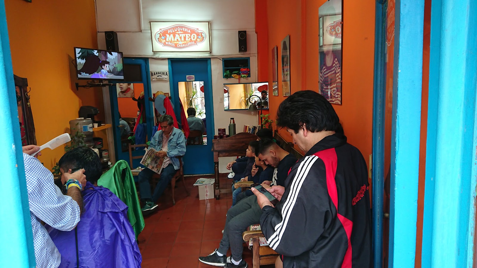 Interior de Peluquería Mateo en Av. Independencia 1754: Mateo cortando el pelo mientras clientes esperan su turno